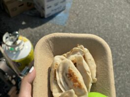 A container filled with pan-fried dumplings and a green frog bun.