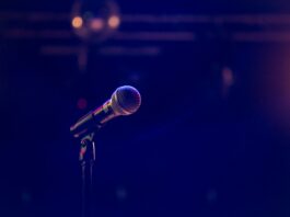 A microphone and stand are washed in a purple-ish light.