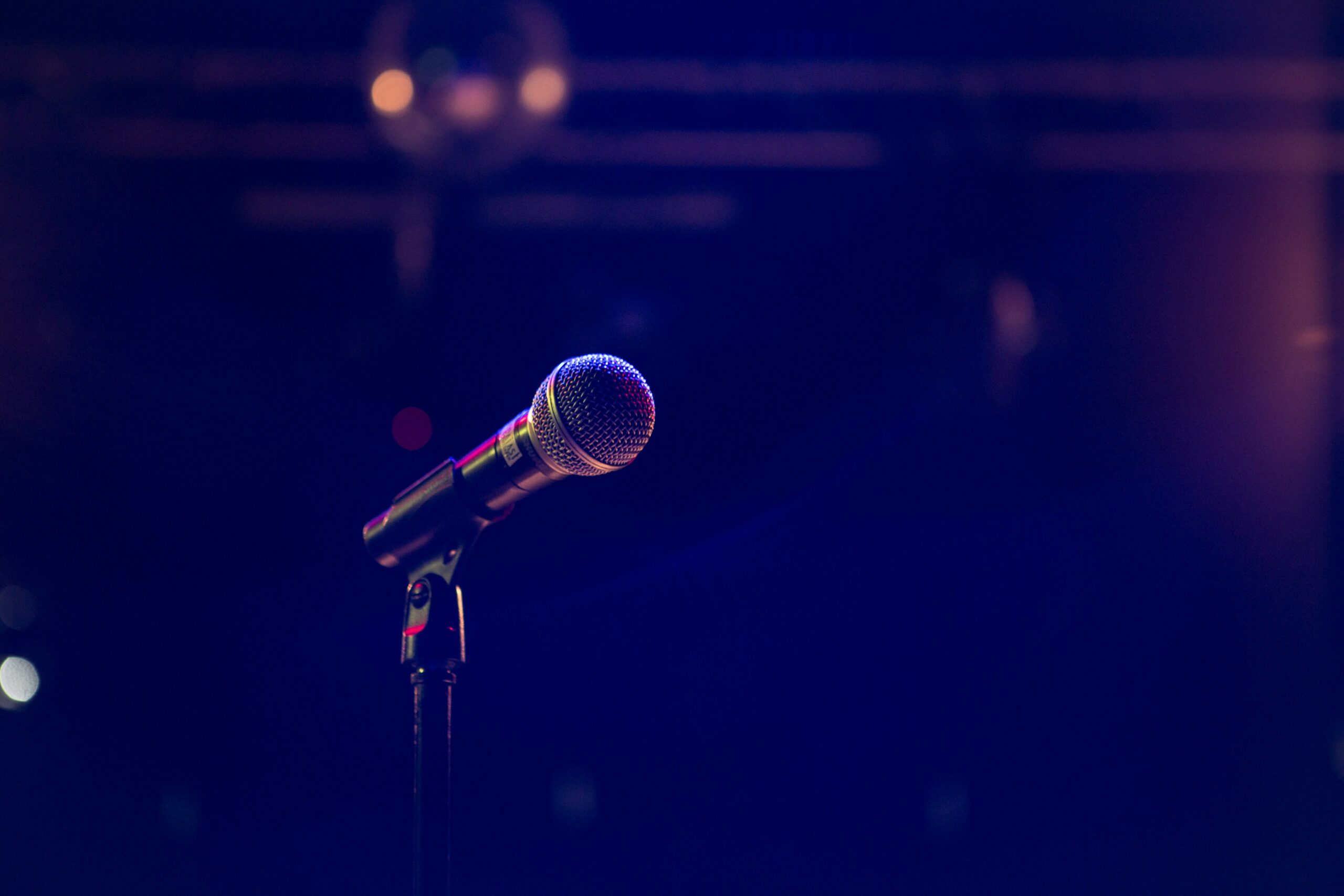 A microphone and stand are washed in a purple-ish light.