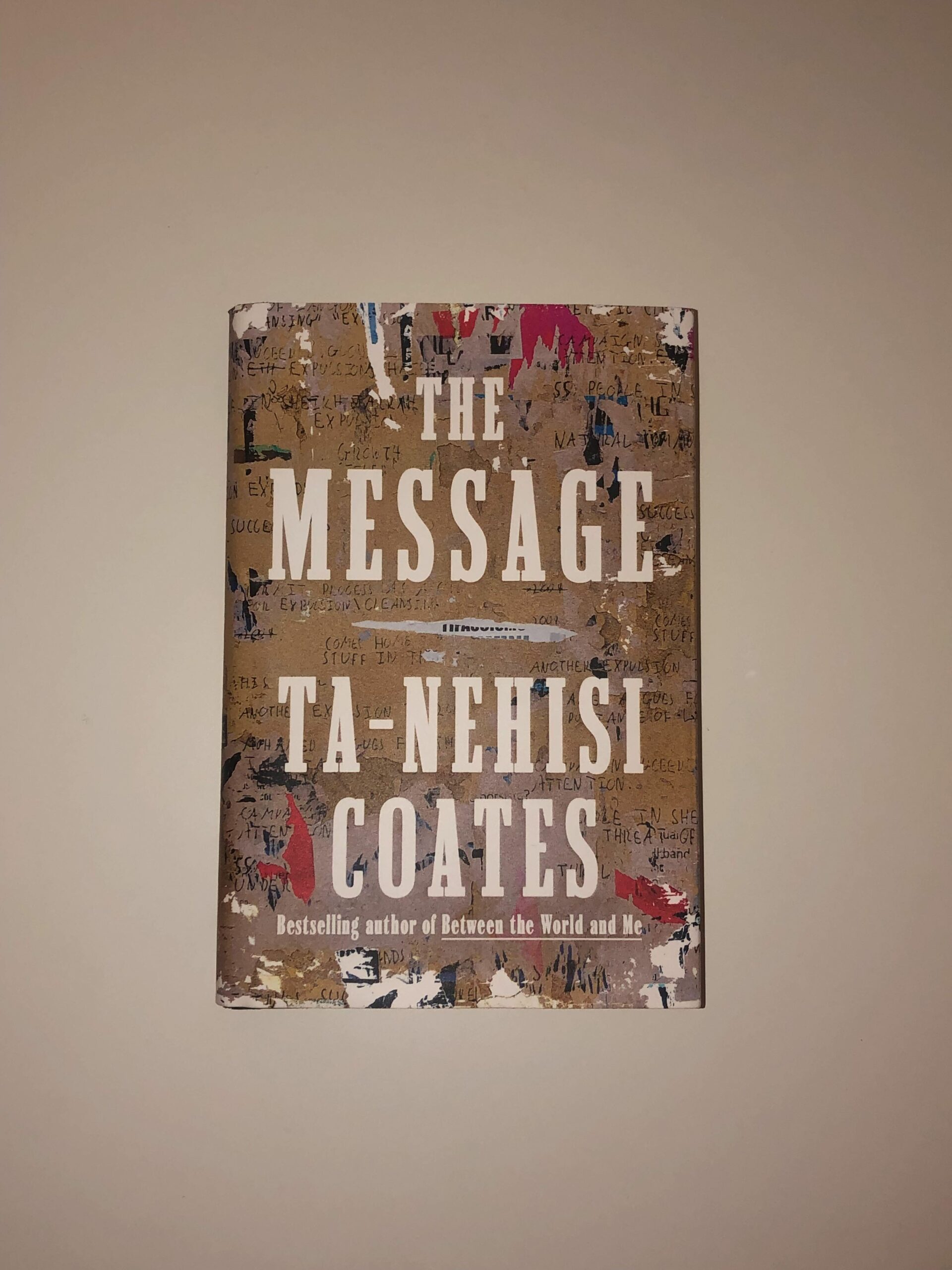 A brown book with a scrapbook-looking design (words written all over, patches of red, black, blue, and white). 'The message' is written in white.