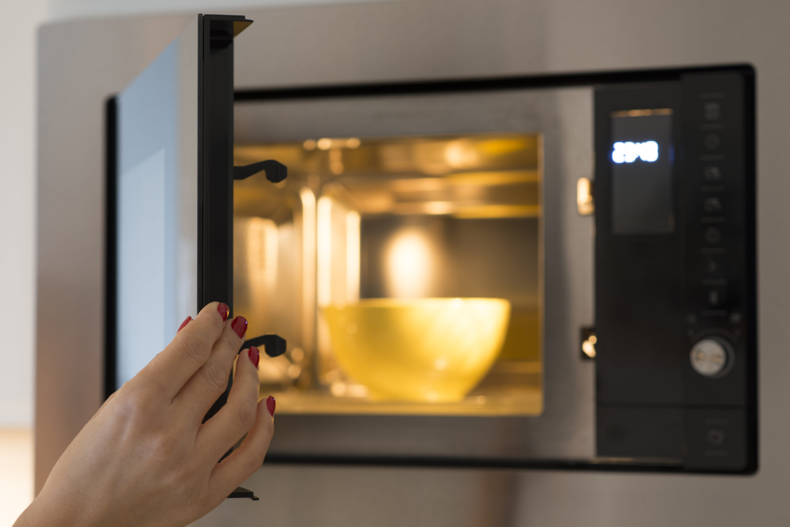 A hand closing a microwave with a bowl inside