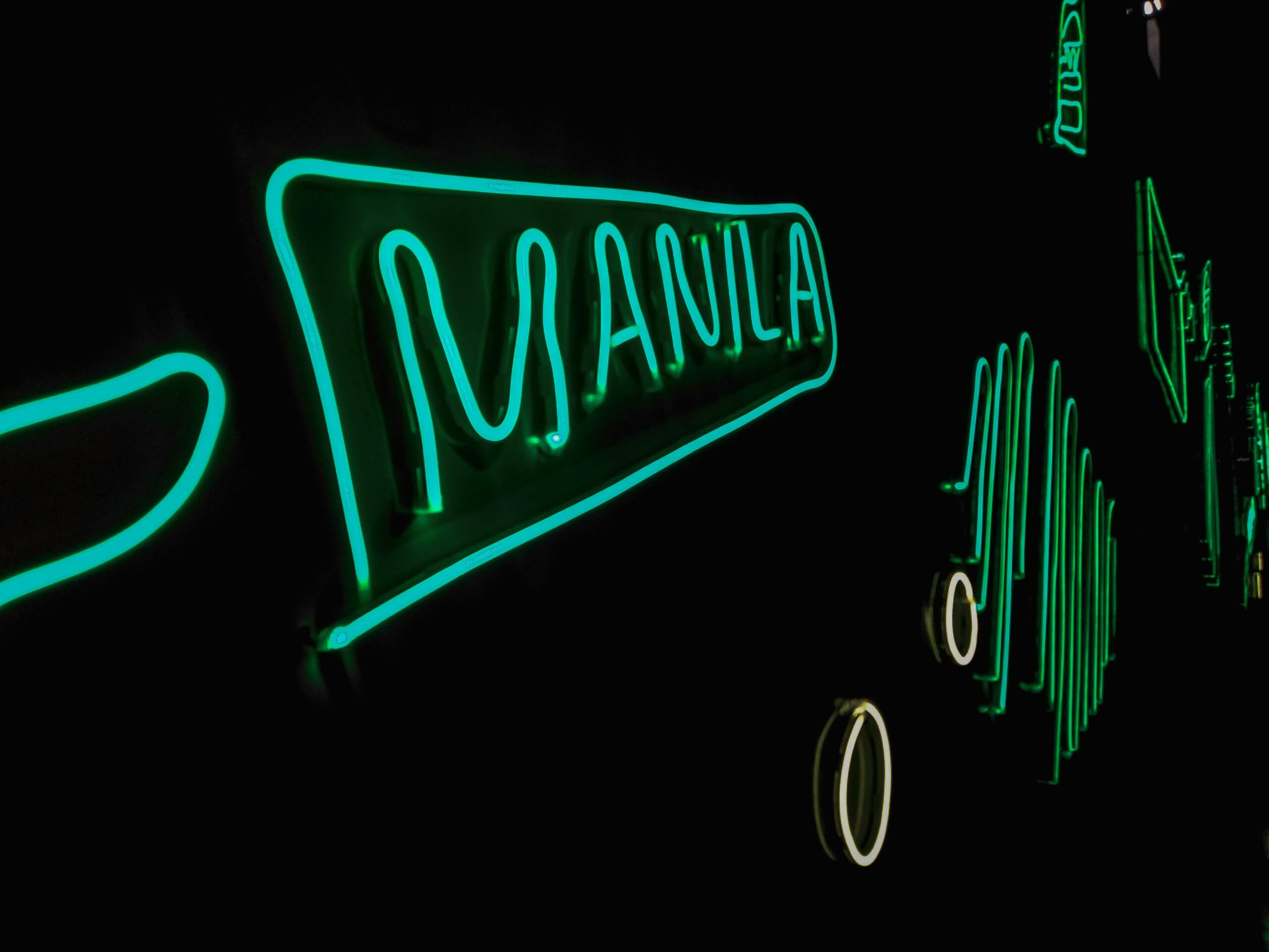 The word 'Manila' written in green light against a dark background.