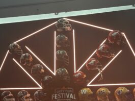 A wall of orange lights and helmets that form a snowflake-like shape. In the middle is a logo that reads “Grey Cup Festival Vancouver 2024.”