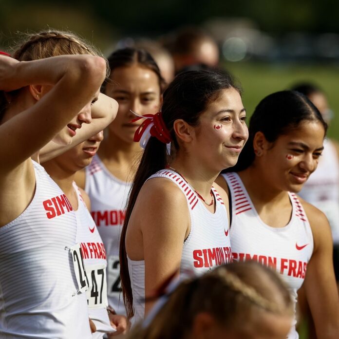 A group of girls wearing white uniforms with red lettering. The words “Simon Fraser” sit at the top of their shirts.