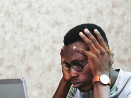 Man sitting in front of a laptop looking frustrated.