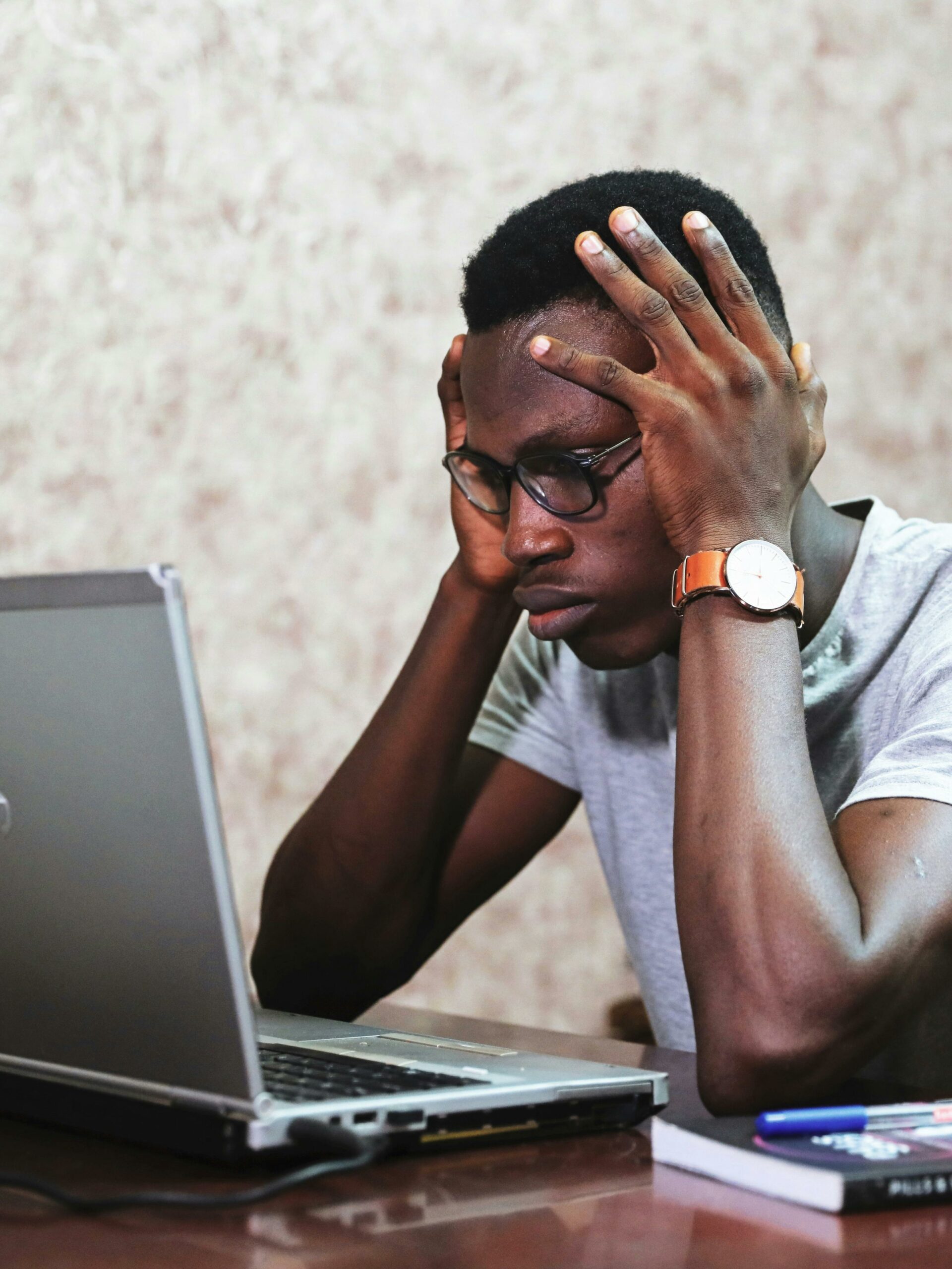 Man sitting in front of a laptop looking frustrated.