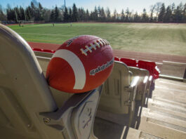 A football sits on the armrest of a seat overlooking Terry Fox field.