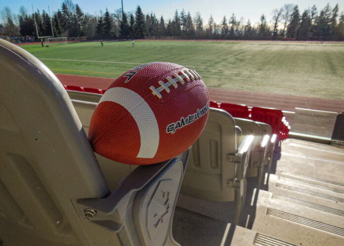 A football sits on the armrest of a seat overlooking Terry Fox field.
