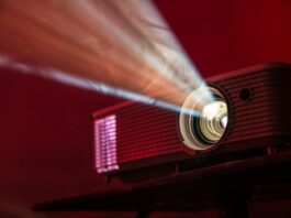 A film projector shines a light through a dark space.