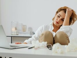 Woman sitting in front of her laptop looking upset. She’s surrounded by used tissues.