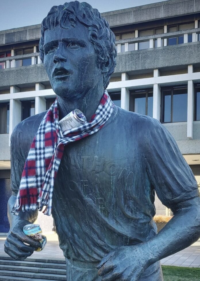 This is a photo of the Terry Fox statue in the AQ courtyard, adorned with a scarf and empty beer cans.