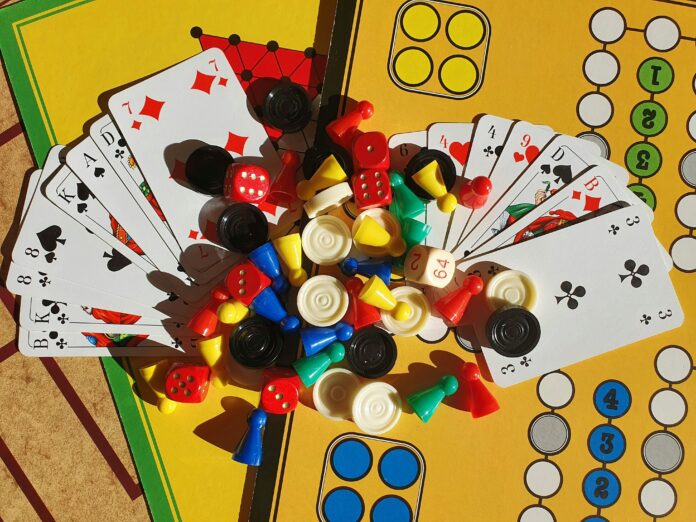 A spread of various tokens and dice used for board games surrounded by cards.
