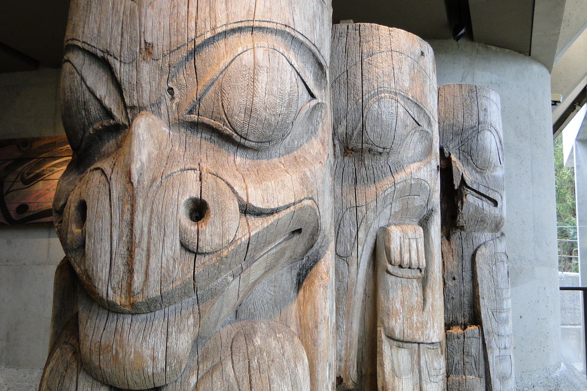 This is a photo of three totems at UBC, one at the forefront and the others stacked behind the first one.