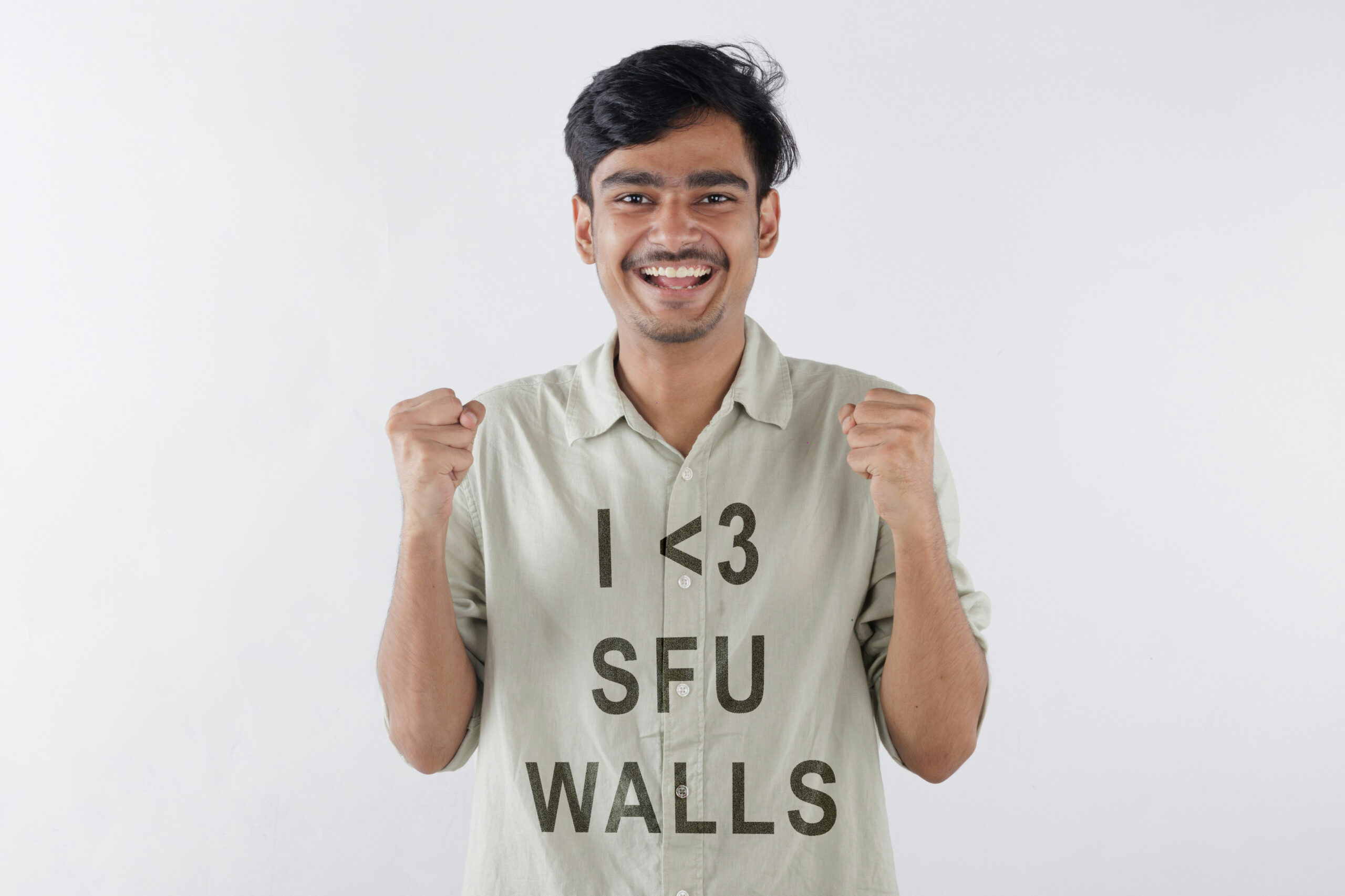 A young man wearing a green t-shirt with the text “I love SFU walls.”