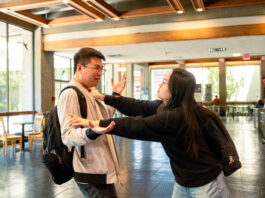 A man shoving a woman out of the way in the hallway of the Academic Quandrangle.
