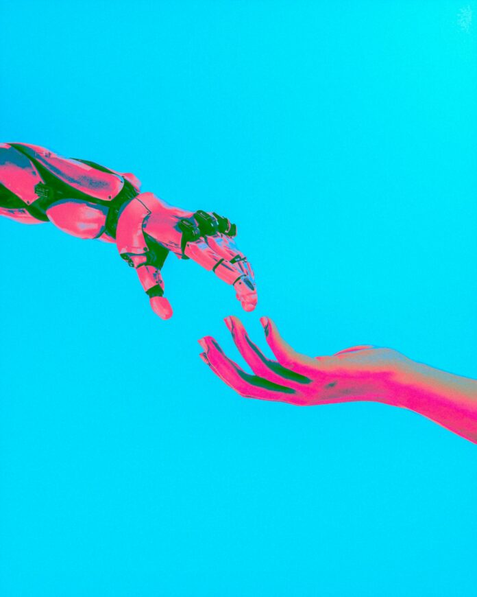 cash-macanaya-AI_unsplash This is an illustration of a robotic arm and hand touching its index finger to a human’s index finger (arm and hand also pictured), mimicking Michelangelo’s “Creation of Adam” painting.