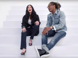 Cher and Future perched upon a white set of stairs in a white abyss. Both have their mouths open, indicating they are singing.