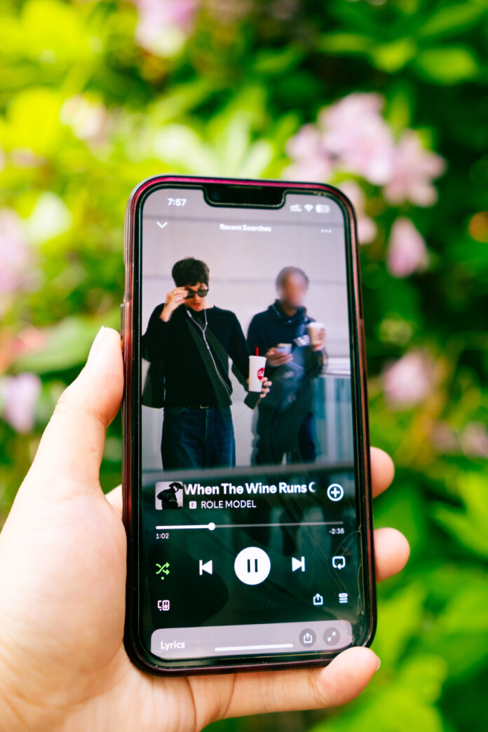 emily-le_spotify-shufflejpg A photo of a person holding a phone with a music app playing “Sally, When the Wine Runs Out” by ROLE MODEL