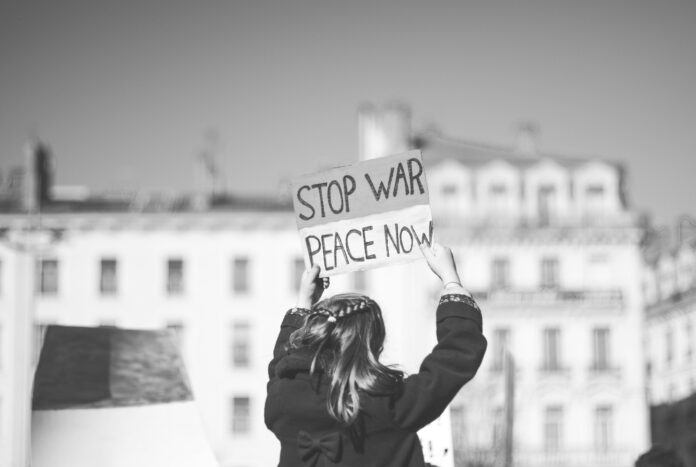 ev-Mz6vYiI8CSA-unsplash A person holding a sign that reads stop war, peace now
