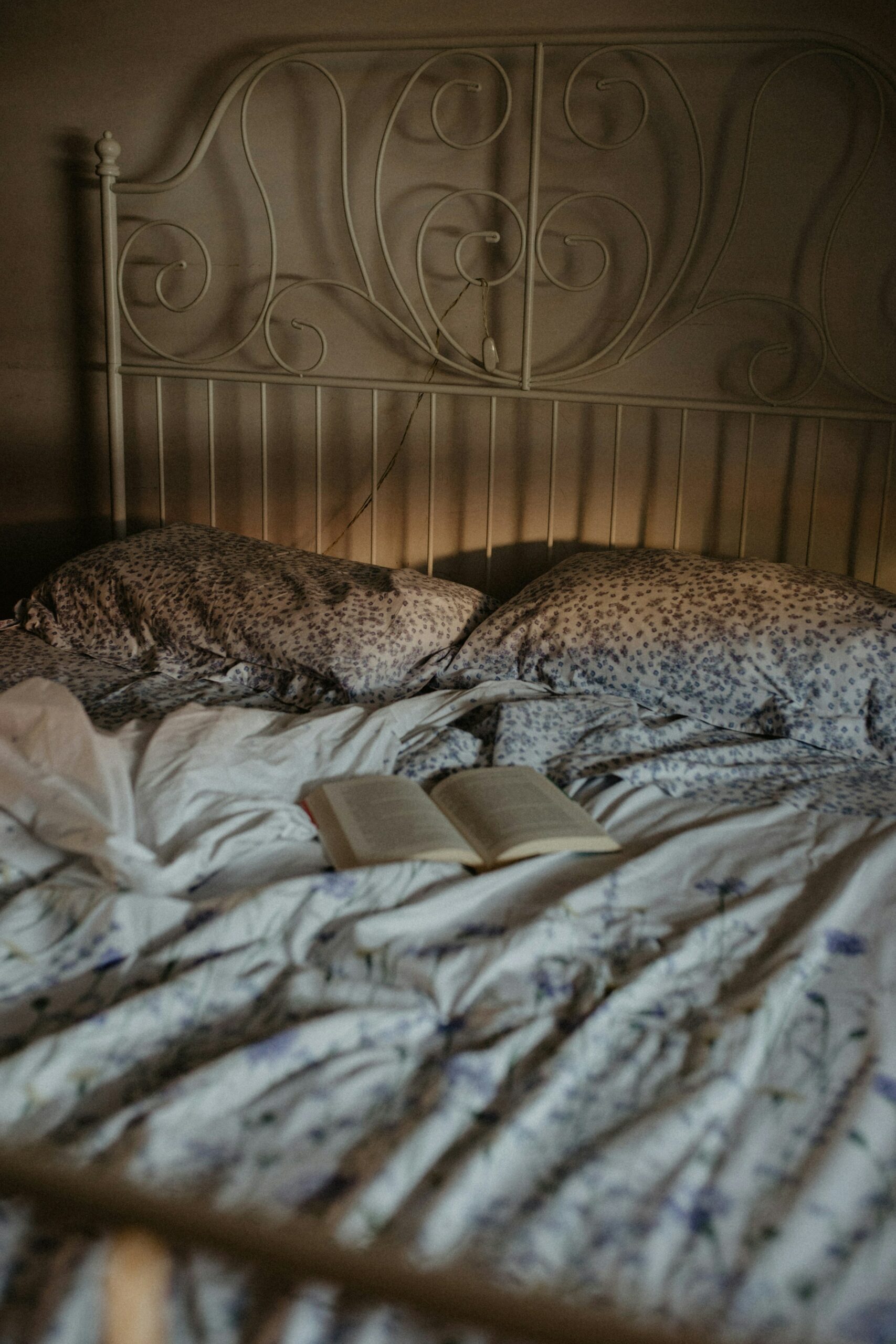 A photo of an opened book on a bed with purple floral sheets.