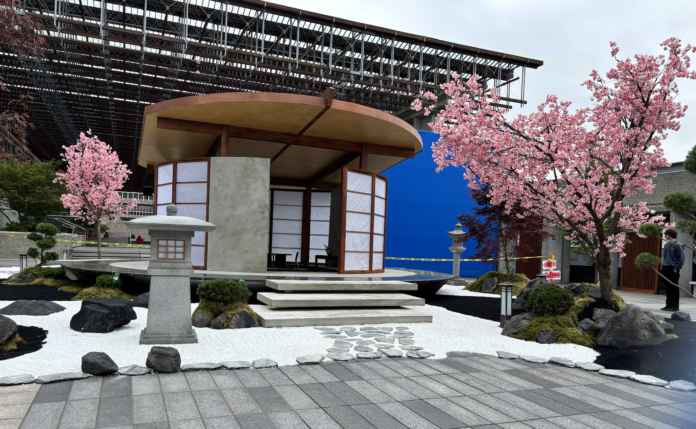 A photo of a scenic garden film set at Burnaby campus with cherry blossom trees and a quaint cabin.