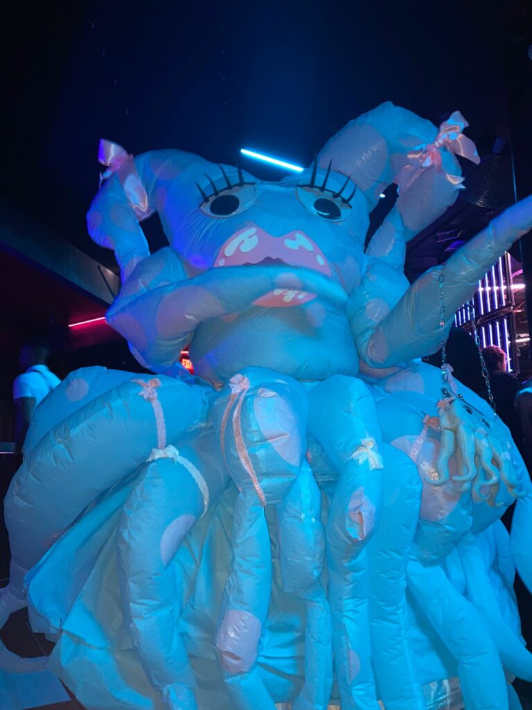 Ash Currie wearing a baby blue and blush pink inflatable octopus costume named Dottie. It was their Bizarre look from the 2024 Platinum Pride Ball in Toronto based on a latex inflatable outfit worn by Lady Gaga.