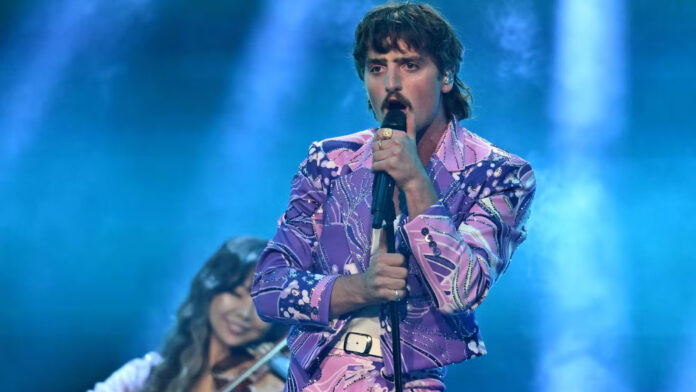 Everyone’s least favourite artist, Benson Boone, performing on stage with a microphone stand in his hands. He’s giving Freddie Mercury energy.