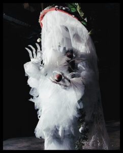 Ash Currie walking in the Bizarre category at the 2023 Supernatural kiki ball in Vancouver wearing an ethereal red and white mushroom costume. They’re holding a smaller red and white mushroom in their hand.