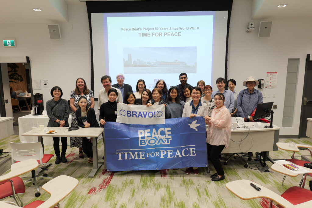This is a photo of all the people from Peace Boat and Mines Action Canada who gave the presentation. One sign they’re holding says “Peace Boat: Time for Peace,” and another smaller sign reads, “Bravo!” It appears some people attending the event also joined in for the photo.