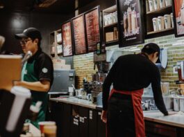 Starbucks CEO addresses store closures and layoffs Employees working inside a bustling Starbucks.