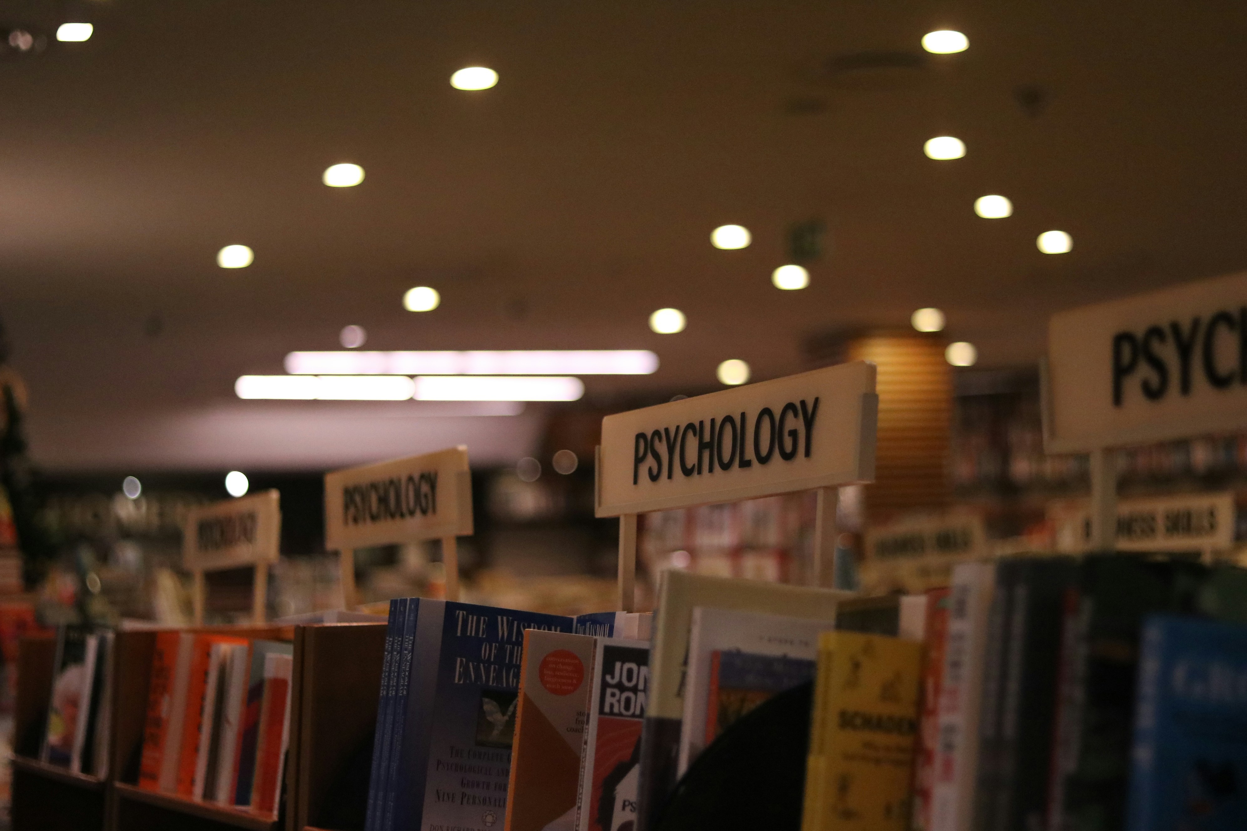 a shot of an aisle in a bookstore that is focused on the Psychology books section. The only parts that are visible in the photo is the upper shelf of the bookcases.