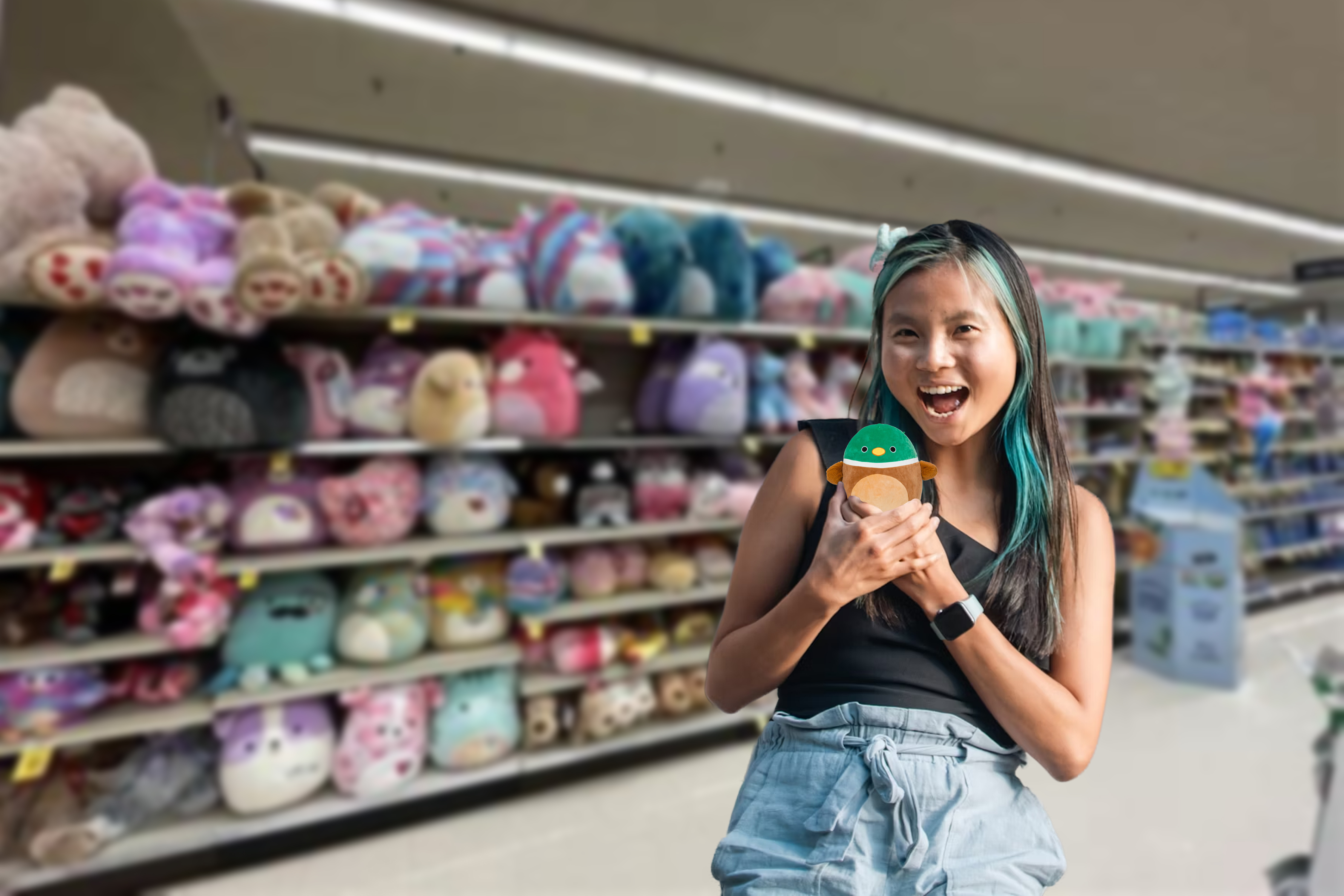 A woman standing in front of a whole bunch of Squishmallow, holding a Squishmallow.