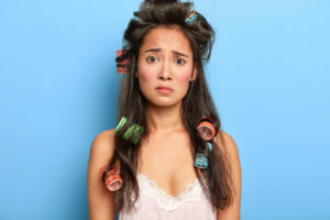 A chaotic-looking lady with hair curlers all tied up in her hair.