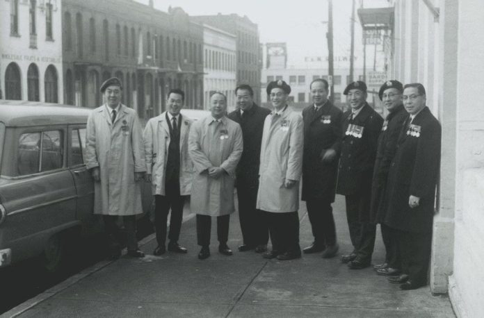 Nine Chinese Canadian veterans stand side-by-side in a black and white photograph from 1981.
