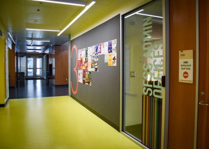 a photo of the SFSS’s admin office on the third floor of the Student Union Building on the Burnaby campus. The photo is taken from the outside of the office, from the hallway. The hallway is empty of people.