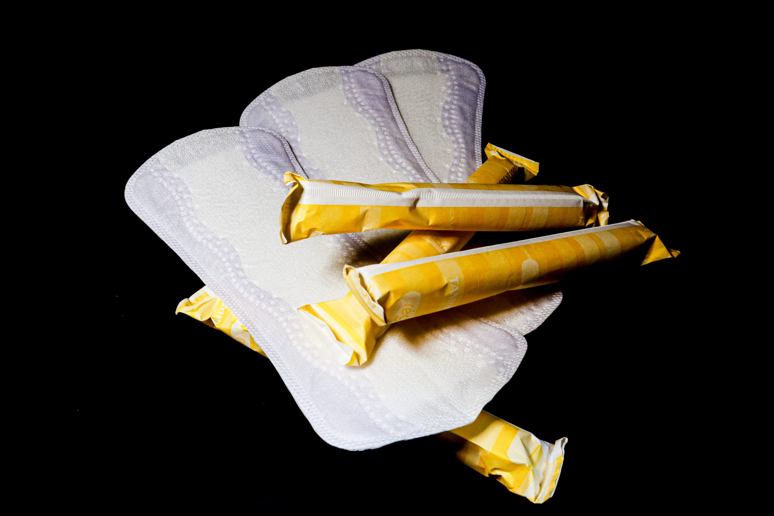 Several tampons and pads are laid out against a black background.