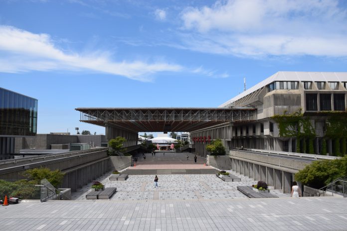 Convocation Mall is pictured on a bright day. A few people are walking around, and the sky is bright blue.
