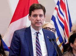 David Eby speaks at a podium with a serious look on his face.