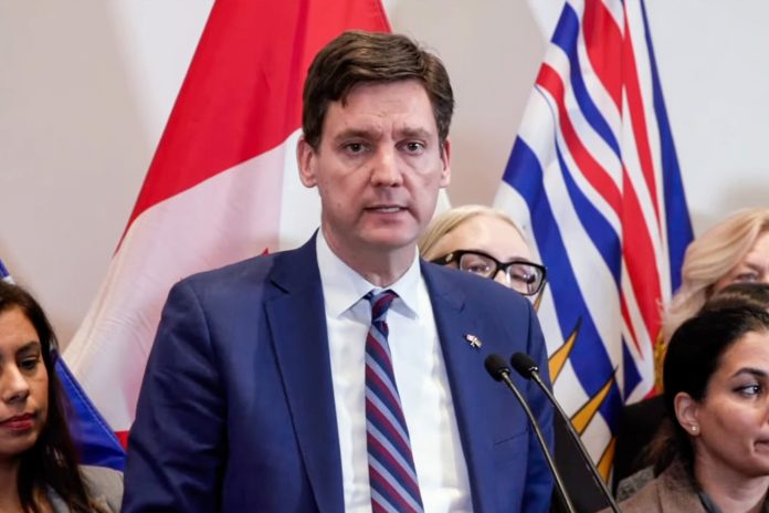 David Eby speaks at a podium with a serious look on his face.