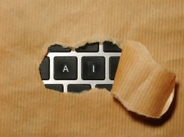 A closeup of a cardboard ripped in the middle revealing a laptop keyboard underneath