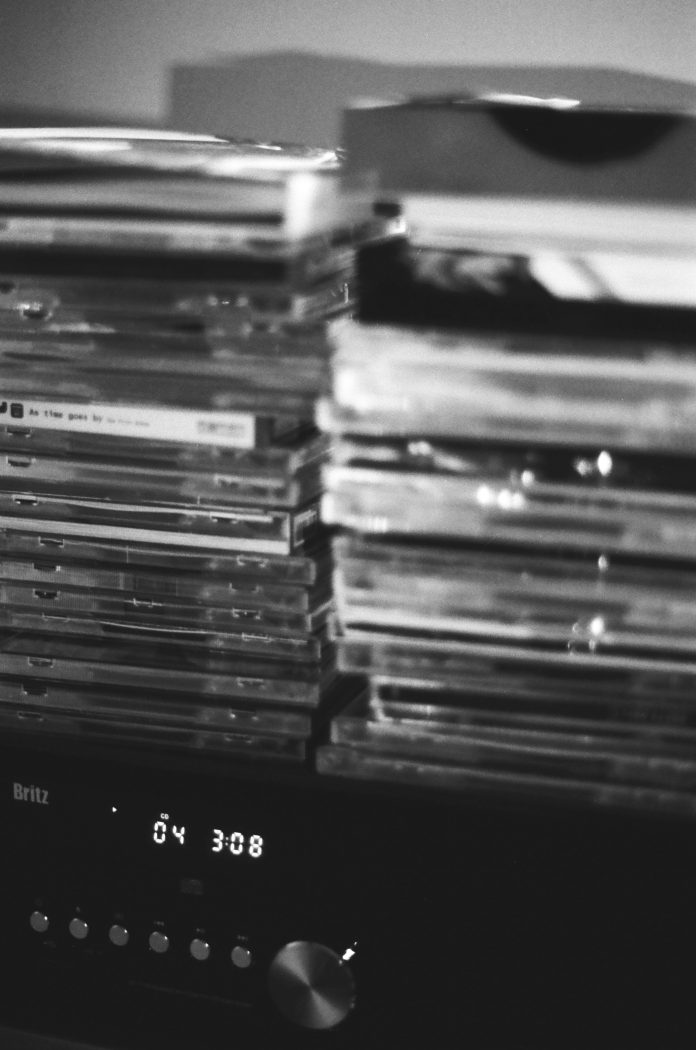 a black and white photo of a stack of CDs on top of a CD player.