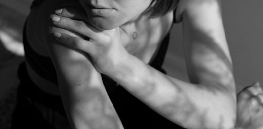 Calls emerge for increased program funding for BC sex workers A woman’s lower body is pictured in black and white while her face is cropped out. The lighting is serious. The woman’s arm is crossed over onto her shoulder, and she looks off to the side.