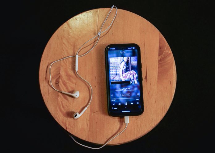 A phone open to the Qobuz app, plugged into wired headphones, playing the song "Everything is free" by Gillian Welch