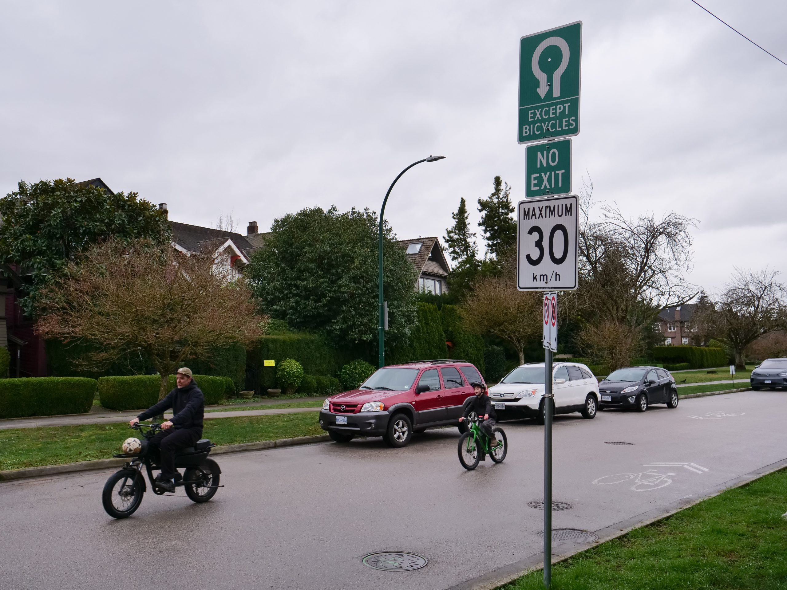 A man and boy bike along a bike road in the suburbs.