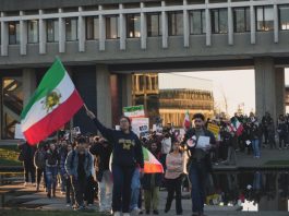 SFU students rally in solidarity with Iranians amid ongoing protests A large group of students march through the middle of the Academic Quadrangle with Iranian flags and signs at sunset.