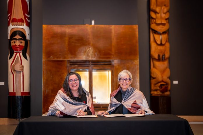 SFU president Joy Johnson and First Nations Health Authority CEO Monica McAlduff smile for the camera as they sign a Memorandum of Understanding.