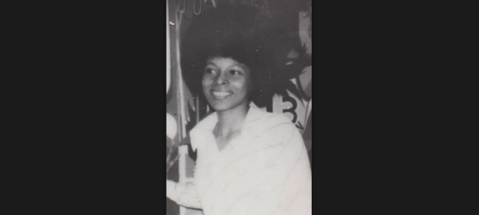 A black and white photo of Assata Shakur smiling.