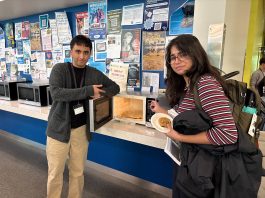 The rivalry between The Ubyssey and The Peak Two humour editors stand next to a microwave with spaghetti spilled all over the inside.