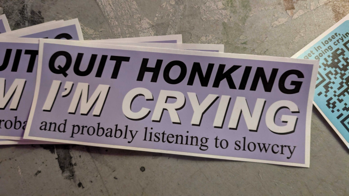 A photo of a promotional sticker from slowcry that says “Quite Honking, I’m Crying and probably listening to slowcry”