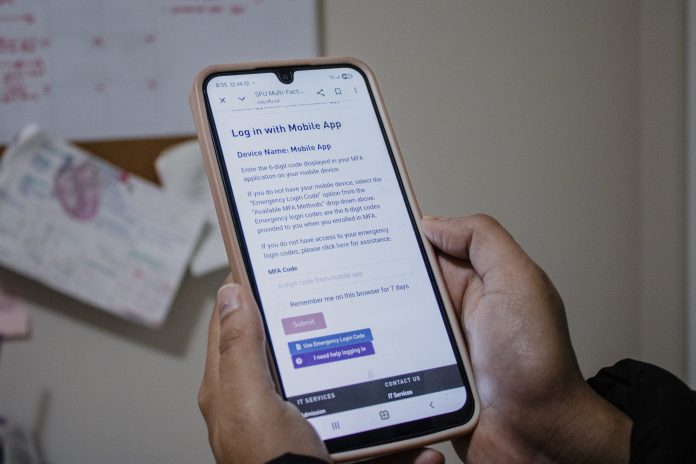 a photo of a person holding a phone in their hands. They’re trying to log onto an SFU portal, but are stopped by SFU’s multi-factor authentication.